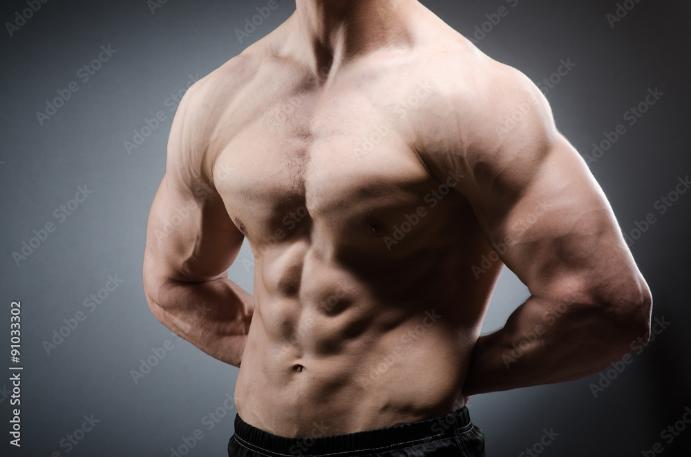 Muscular man posing in dark studio