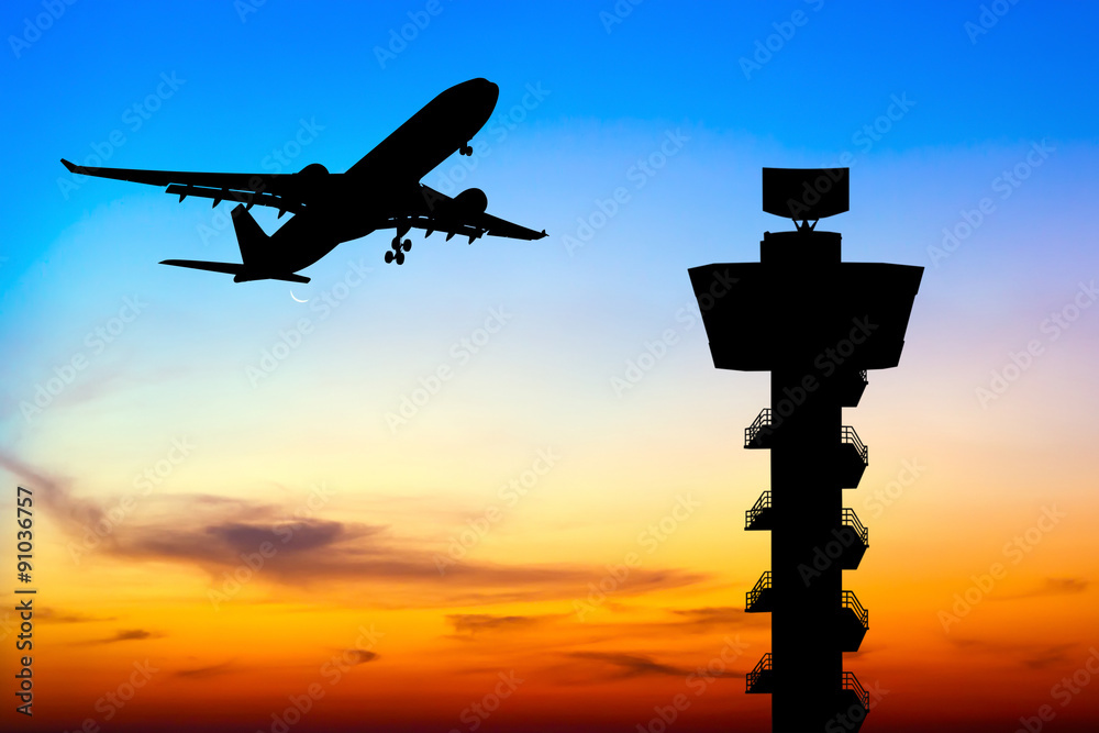 Fototapeta premium Silhouette commercial airplane take off over airport control tow
