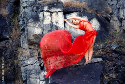 девушка в красном платье , на камнях занимается йогой