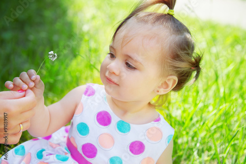 Cute little girl wearing polka dots dress sitting on the grass 