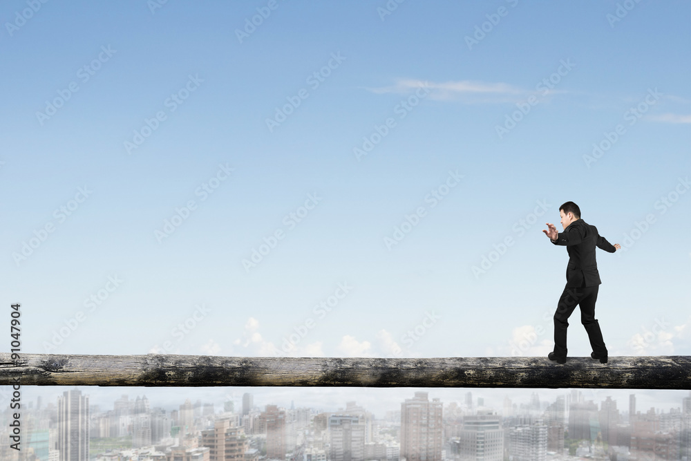 Businessman balancing on tree trunk high in the sky Businessman balancing on tree trunk high in the sky