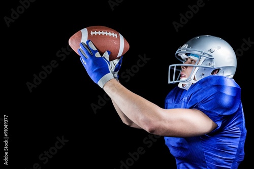 Side view of American football player looking at ball