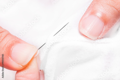 women s hands while sewing white cloth
