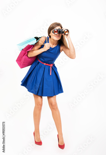 Girl with the shopping bags looking through the binoculars © rodjulian