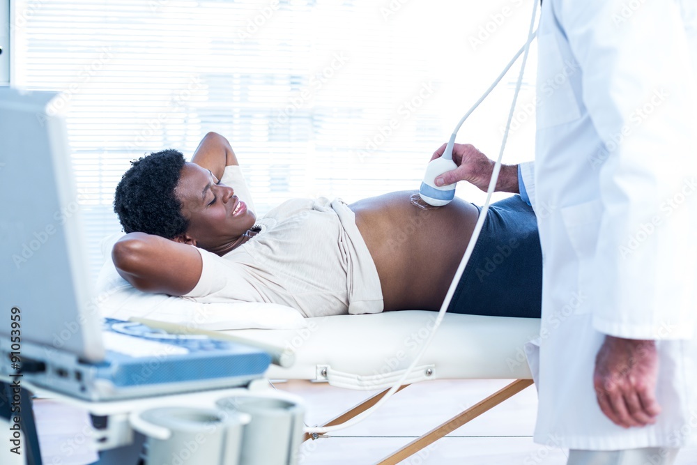 Male doctor applying applying gel on belly Male doctor applying applying gel on belly