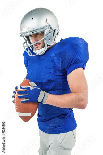 American football player holding ball while looking away