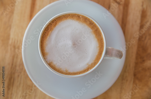 A cup of coffee with in a white cup on wooden background
