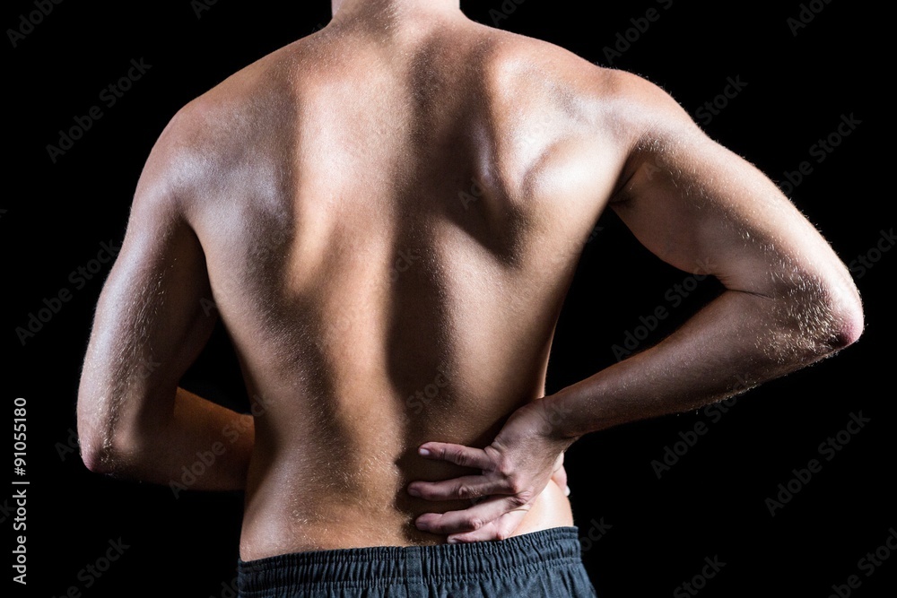 Rear view of shirtless man with back pain Rear view of shirtless man with back pain