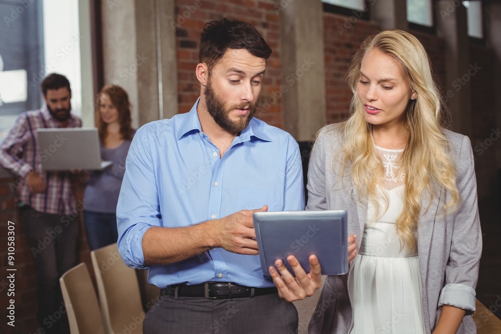 © WavebreakMediaMicro - Business colleagues discussing over digital tablet