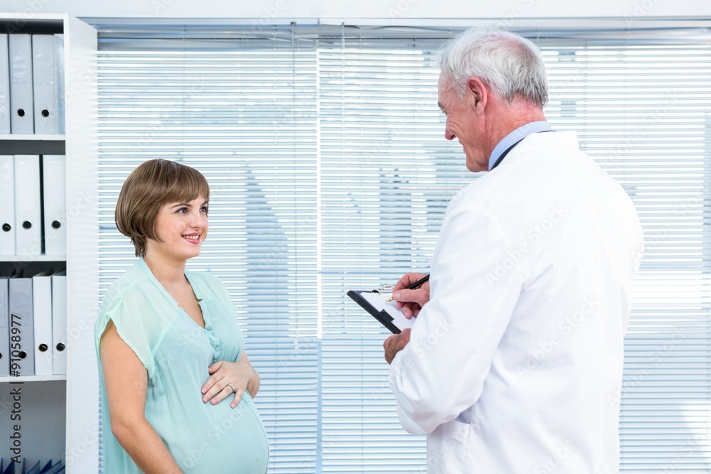 Obraz premium Happy pregnant woman talking with doctor
