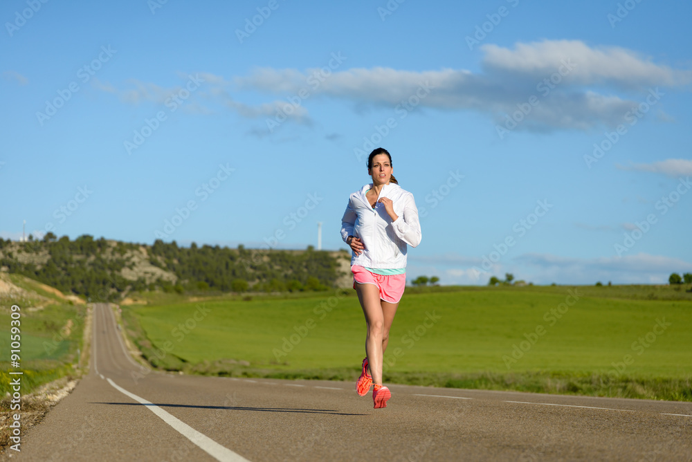 Sporty motivated woman running on country side road. Female athlete training outdoor. Sporty motivated woman running on country side road. Female athlete training outdoor.