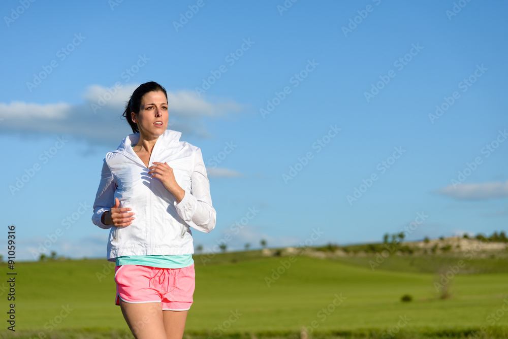 Sporty woman running and training at countryside field. Motivated female runner exercising. Sporty woman running and training at countryside field. Motivated female runner exercising.