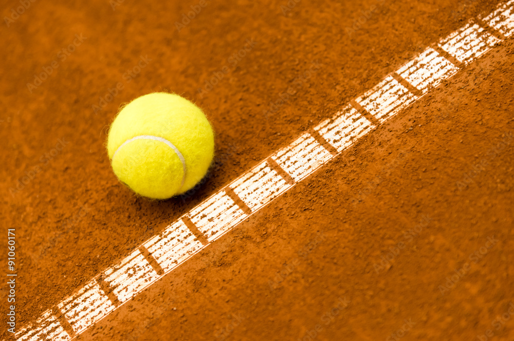 yellow tennis ball on a red clay court 