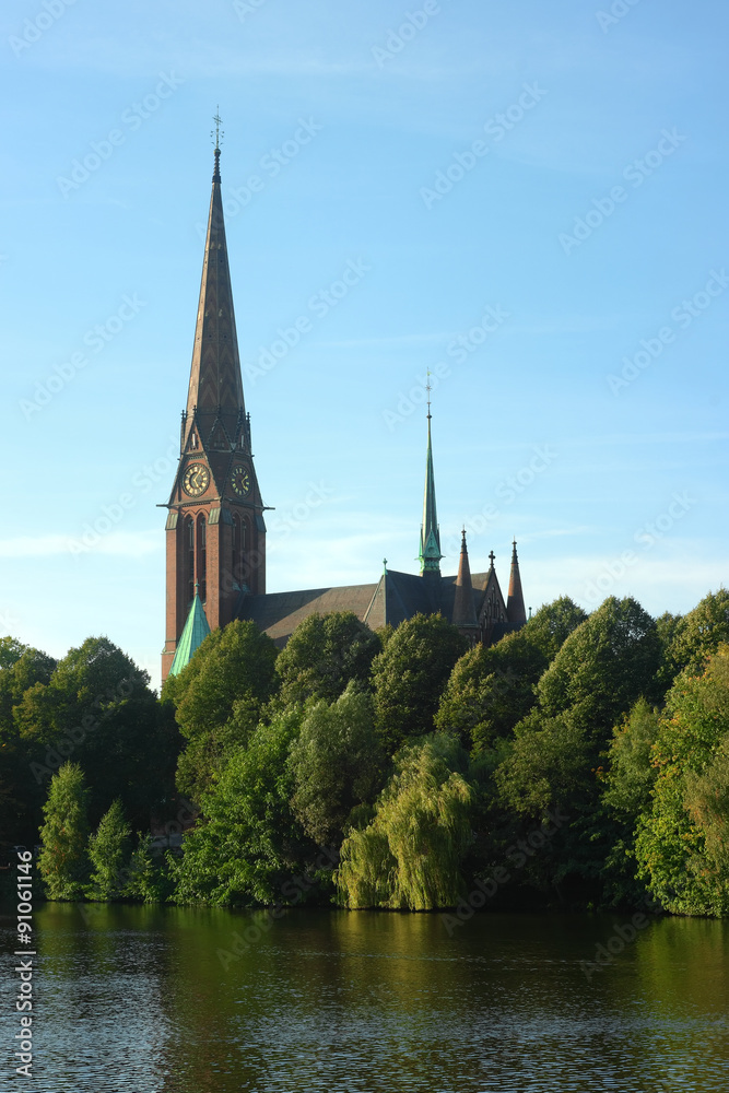 The Church of the St. Gertrude in Hamburg. Urban landscape with the clock tower of church and city park over the water. Hamburg.