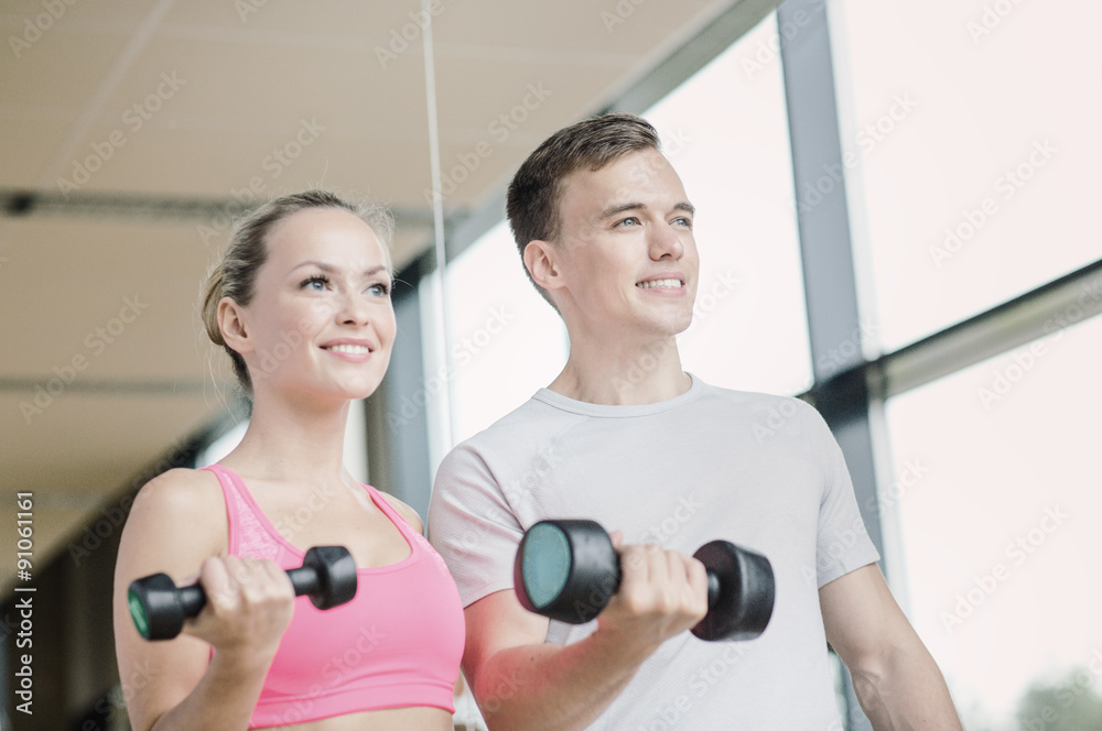 smiling young woman with personal trainer in gym smiling young woman with personal trainer in gym