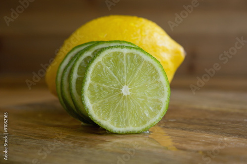 Lemon and slices of lime on wood background 