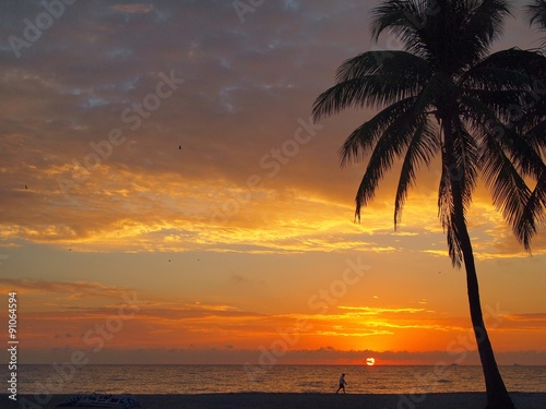 silhouette of man walking alone on beach at sunrise