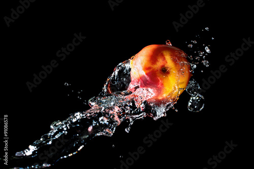 Peach with fresh water splash against black background