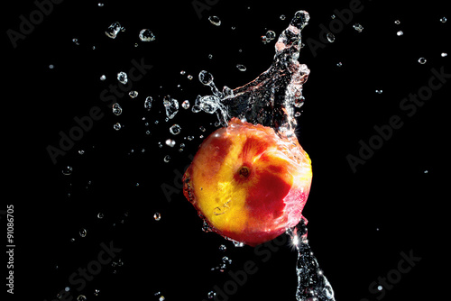Peach with water splash on black background