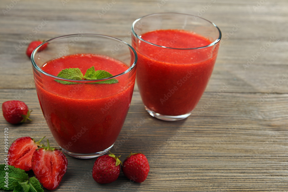 Glasses of strawberry smoothie with berries on wooden table close up Glasses of strawberry smoothie with berries on wooden table close up