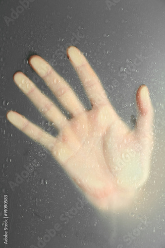 Female hand behind wet glass, close-up