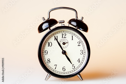 Black old fashioned alarm clock on beige background.