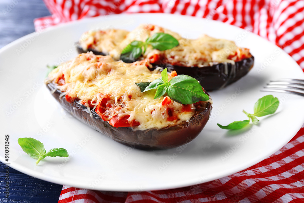 Dish of eggplant with cherry tomatoes and cheese in white plate on red napkin, closeup Dish of eggplant with cherry tomatoes and cheese in white plate on red napkin, closeup