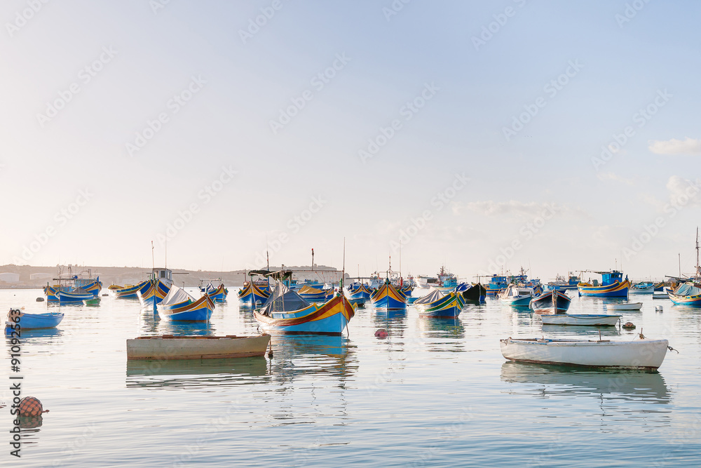Colorful typical boats - Mediterranean traditional fisherman village in the south east of Malta. Early winter morning in Marsaxlokk, Malta.