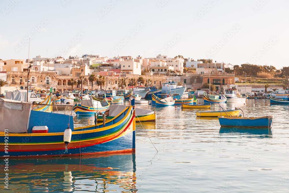 Colorful typical boats - Mediterranean traditional fisherman village in the south east of Malta. Early winter morning in Marsaxlokk, Malta.