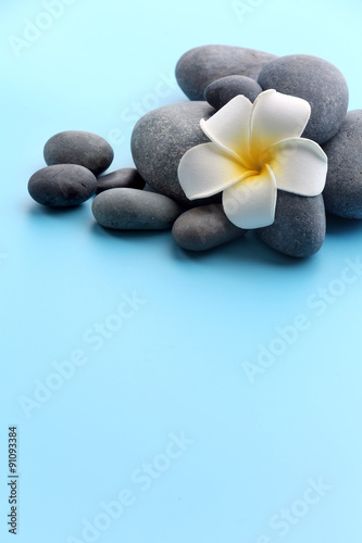 Spa stones with flower on blue background