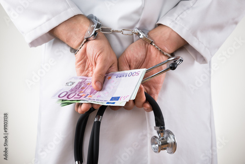 Doctor Hands With Bank Notes And Handcuffs