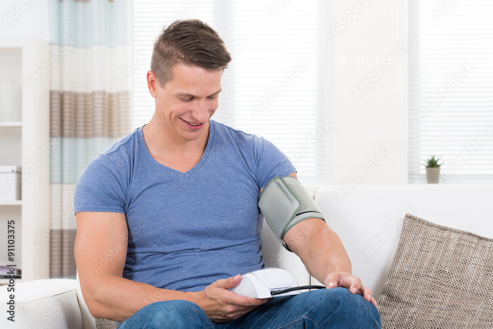 Man On Sofa Checking Blood Pressure Man On Sofa Checking Blood Pressure