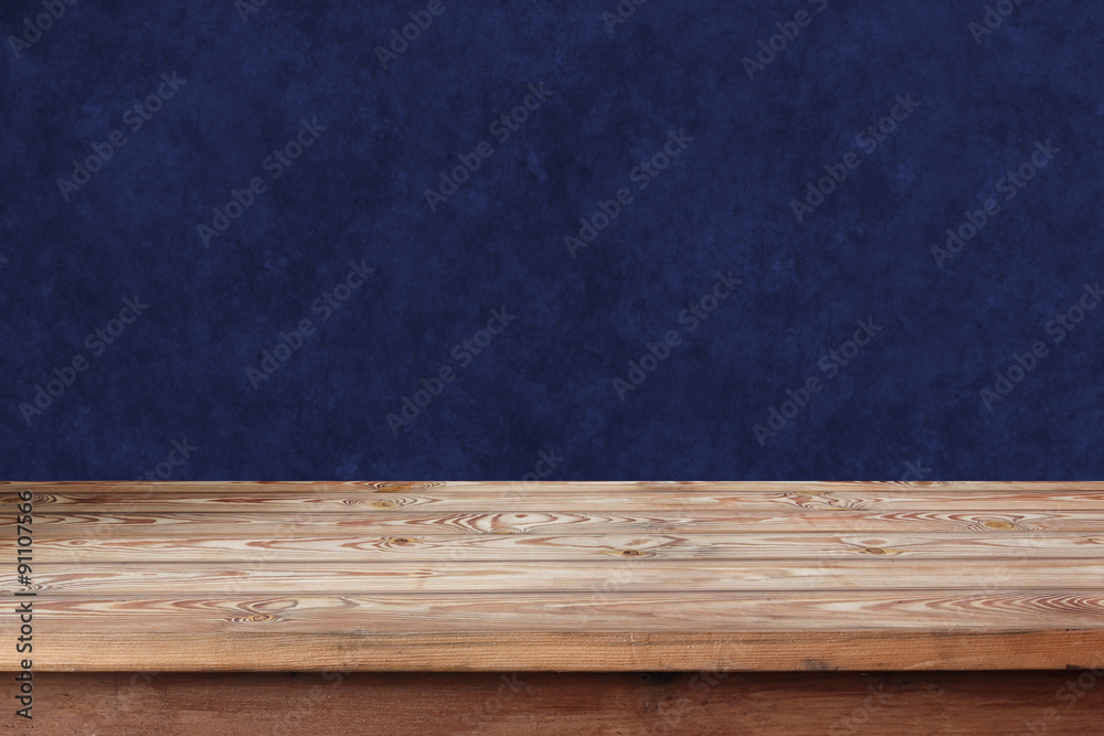 Empty wooden table against a blue wall.