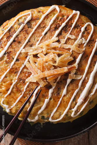 Japanese fast food: okonomiyaki close-up and chopsticks. Vertical
 photo