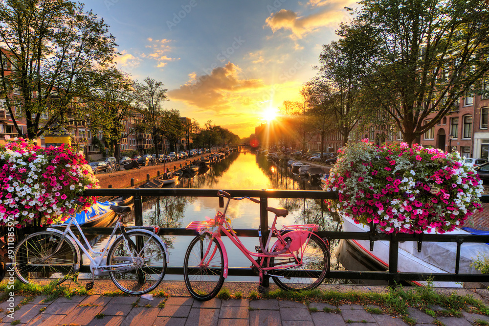 Beautiful sunrise over Amsterdam, The Netherlands, with flowers and bicycles on the bridge in spring