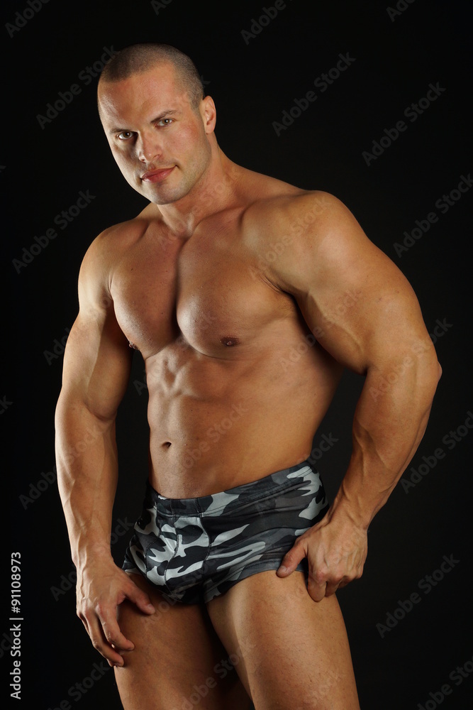 Fototapeta premium Handsome standing muscular man and poses on gray background