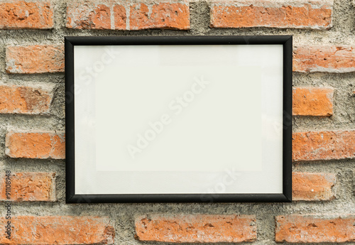 blank black picture frame on old brick wall