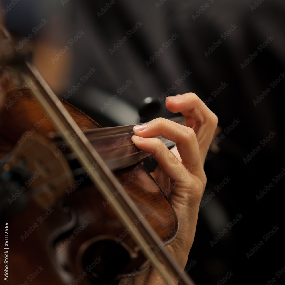 The girl's hand on the strings of a violin in dark colors The girl's hand on the strings of a violin in dark colors