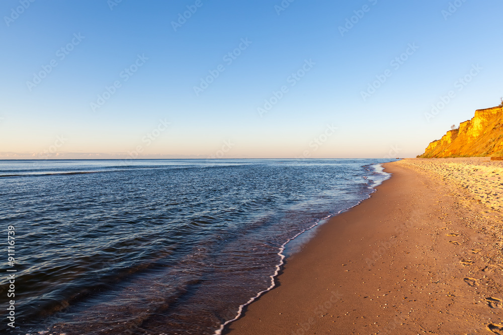 Sea waves on a sandy beach with the dawn sky
