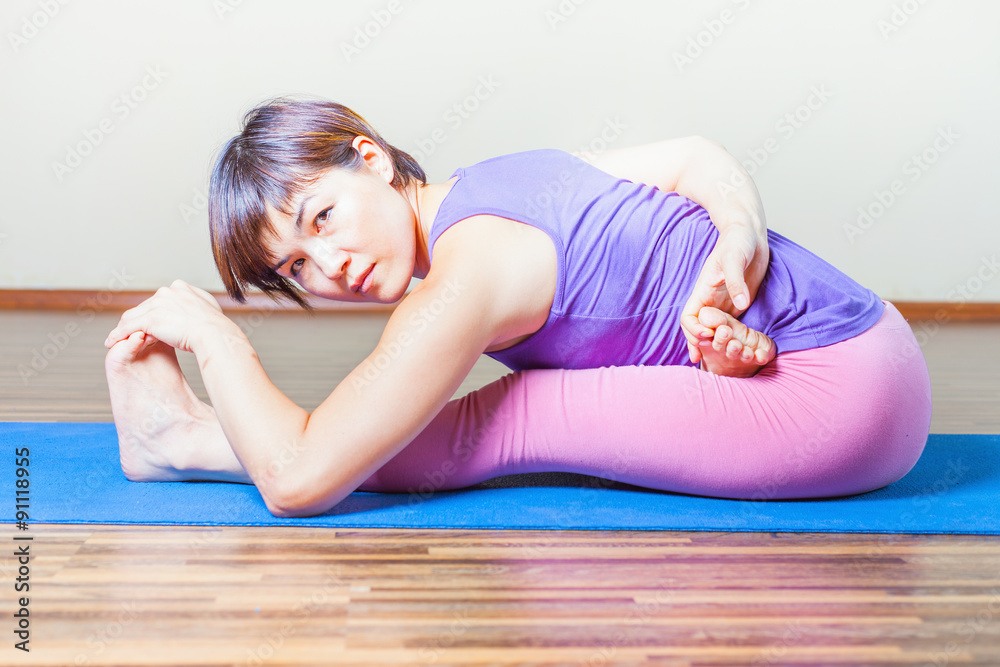 Asian woman stretching at mat before yoga exercise indoor Asian woman stretching at mat before yoga exercise indoor