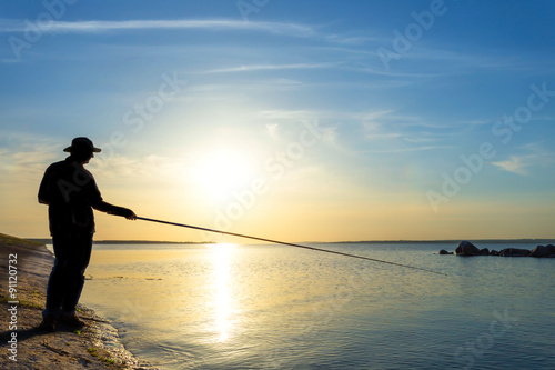 fisher silhouette on a river at the sunset