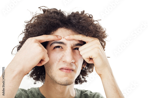 Tableau sur toile Young man squeezes a pimple on him forehead