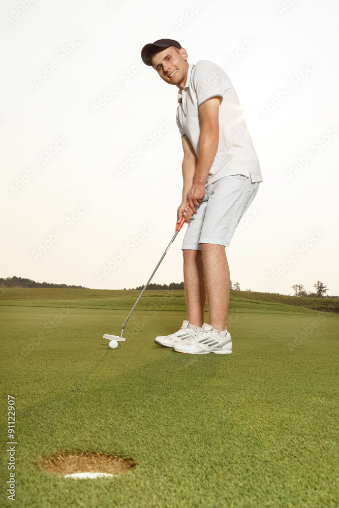 Fototapeta premium Sportsman putting golf ball into a hole