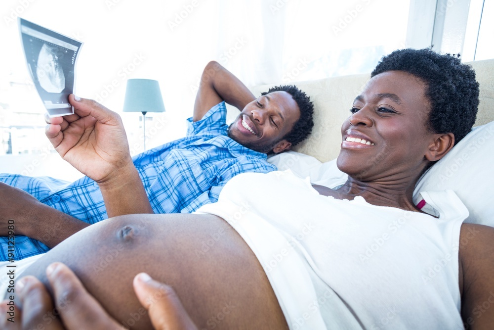 Smiling pregnant woman looking at ultrasound scan Smiling pregnant woman looking at ultrasound scan