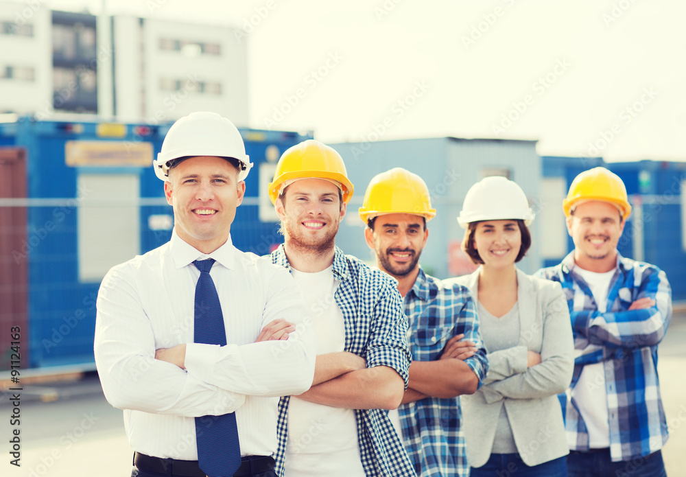 group of smiling builders in hardhats outdoors group of smiling builders in hardhats outdoors