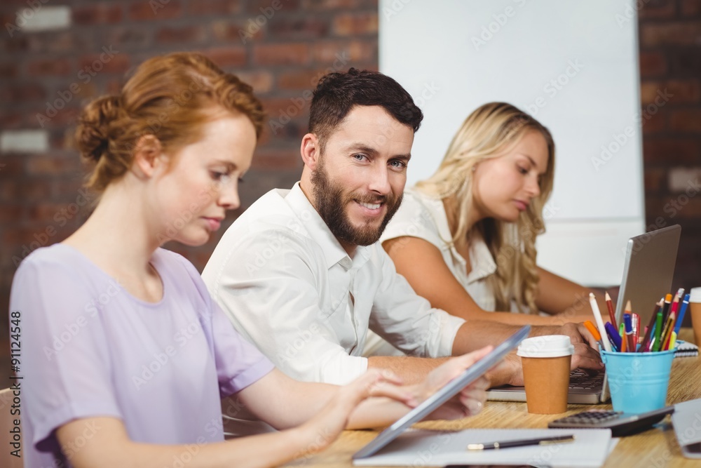 Portrait of smiling man sitting amidst colleagues 