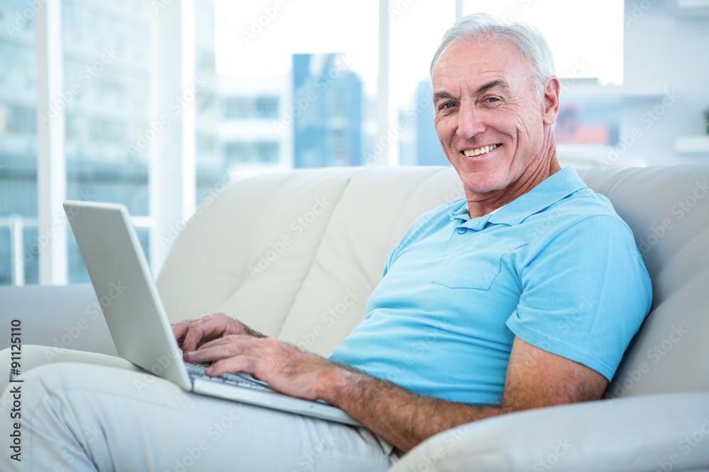Portrait of happy senior man sitting on sofa with laptop Portrait of happy senior man sitting on sofa with laptop