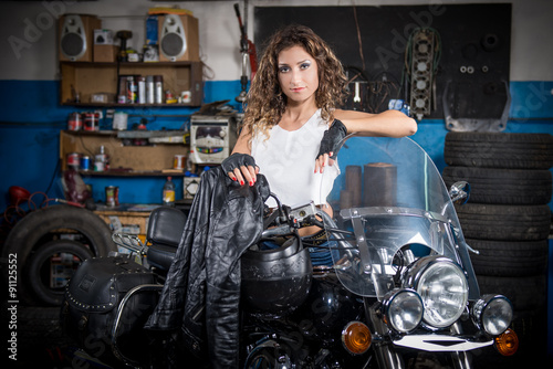 beautiful girl sitting on a motorcycle in the garage. slight blur
