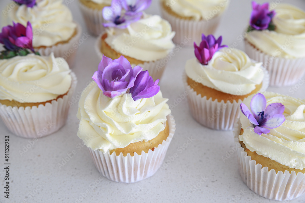 Edible purple freesia flowers on vanilla cupcakes with whipped c Edible purple freesia flowers on vanilla cupcakes with whipped c