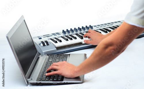 man playing on a synthesizer and writes on a laptop